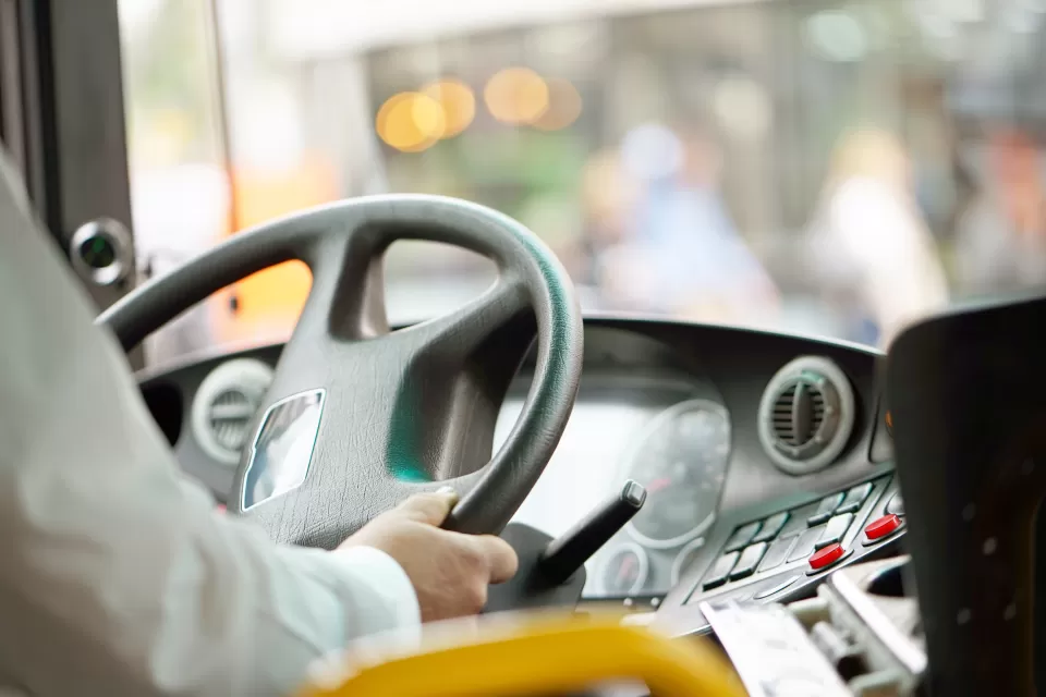 Close-up of bus driver holding bus steering wheel